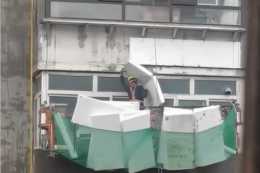 遼寧一工人外牆高空作業遇暴雨，舉泡沫板避雨，網友：太心疼